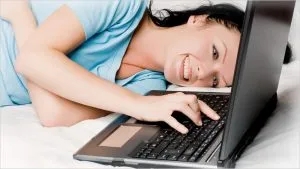 girl laying in bed while typing