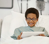 boy with cancer holding tablet