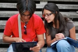 A boy holding tablet with a girl watching near him